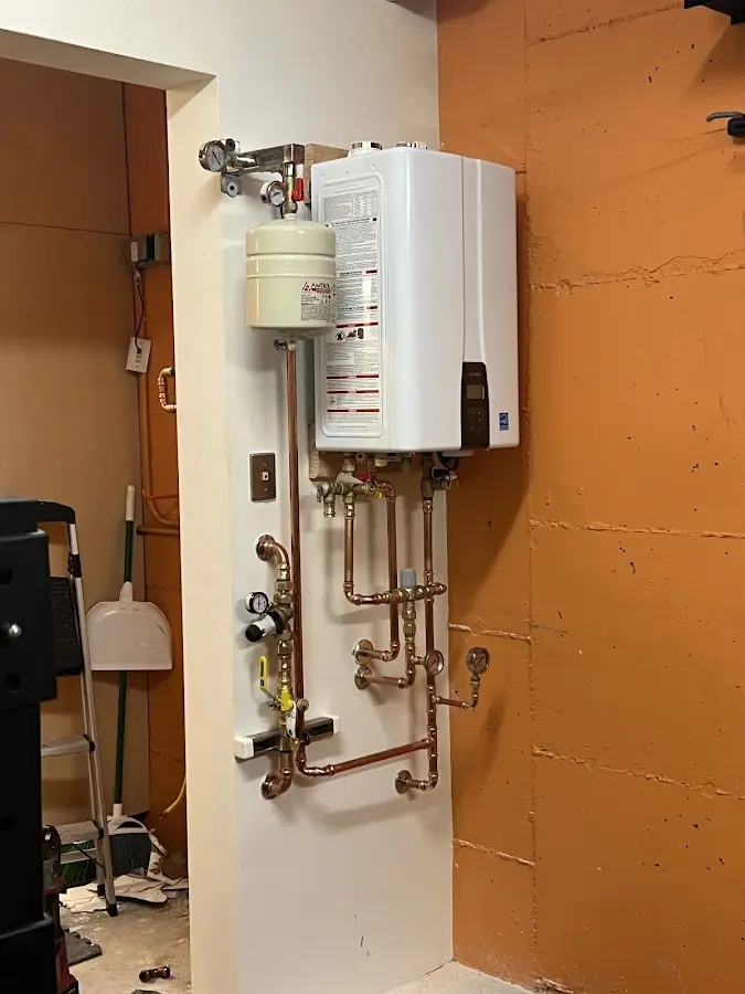 Plumbing technician inspecting water heater connections in North Star